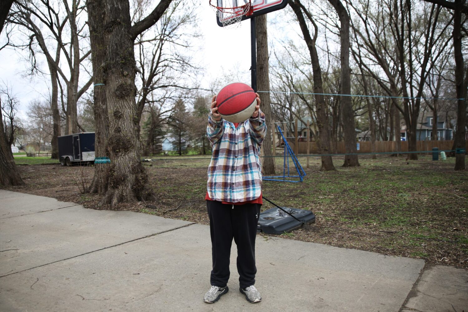 Joey plays basketball with his father in their driveway. He is one South Dakota child impacted by the state’s gender-affirming care ban for trans kids, which has been implemented in several surrounding states. South Dakota Searchlight photo by Makenzie Huber
